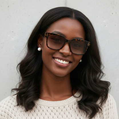 Woman wearing sunglasses and a white sweater against a gray background
