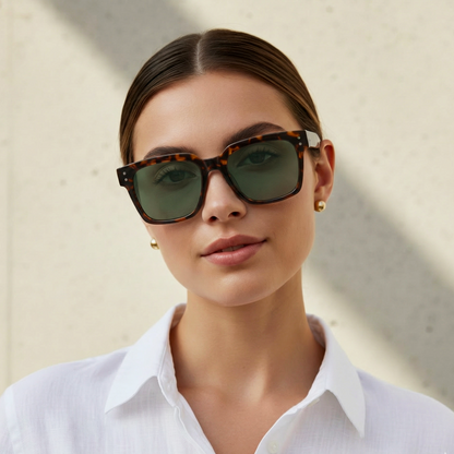 Woman wearing tortoiseshell sunglasses with a neutral background